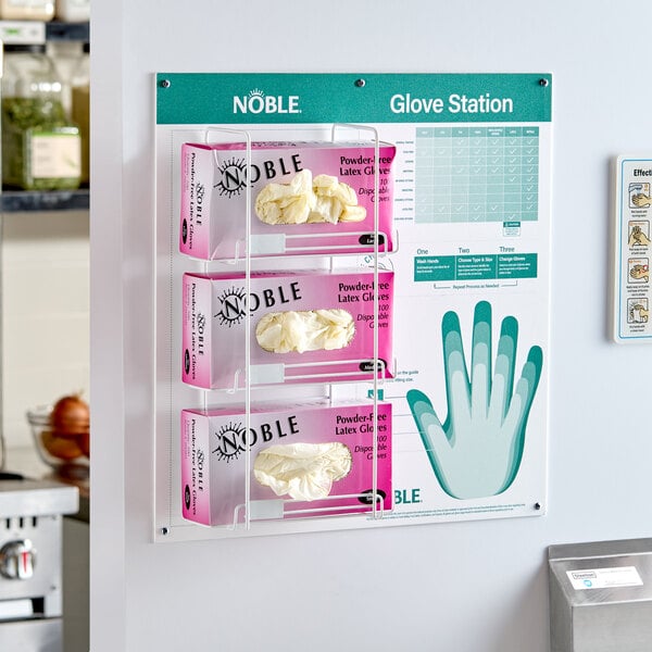 A wall-mounted glove dispenser station holding three boxes of Noble latex gloves with an attached usage guide chart.