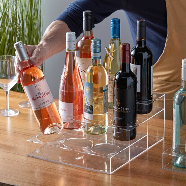 A hand using a Choice 3 Tier Syrup Bottle Organizer to hold a bottle of wine.