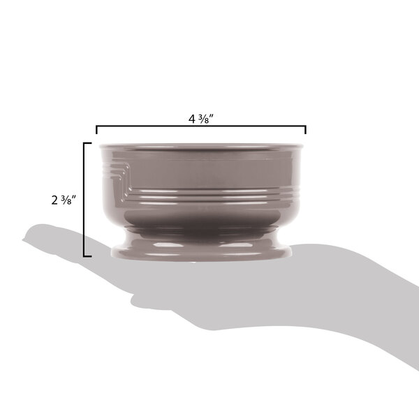 A hand using a measuring cup to fill a small grey Cambro Shoreline bowl.