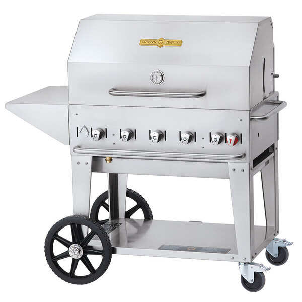 A silver stainless steel Crown Verity mobile outdoor grill with wheels and a stainless steel top.