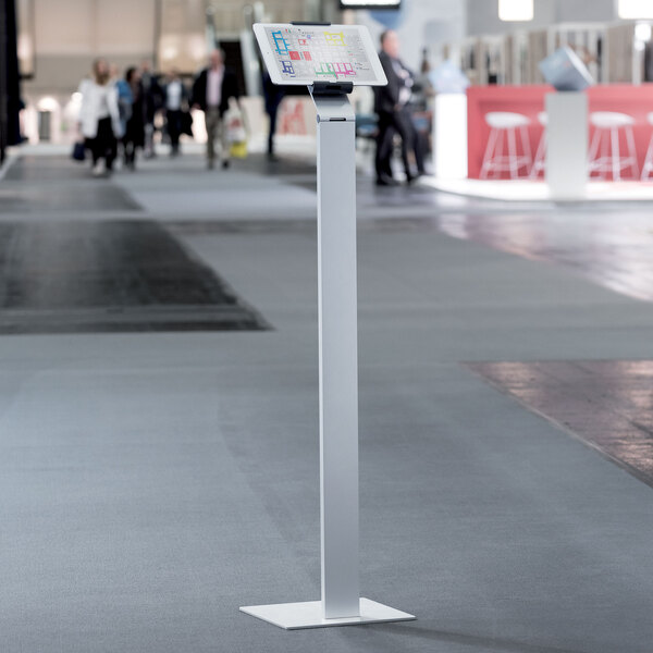 A silver metal floor stand with a tablet on it.