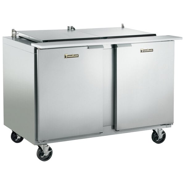 A stainless steel Traulsen refrigerated sandwich prep table with two doors on wheels.