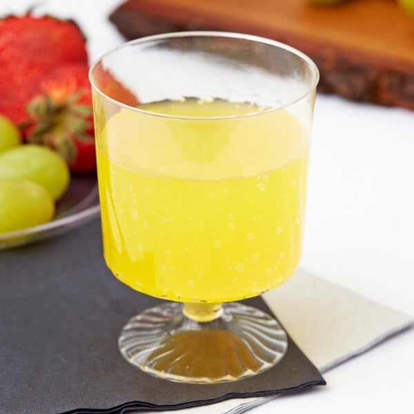 A close-up of a Fineline Flairware clear plastic wine cup filled with yellow liquid.