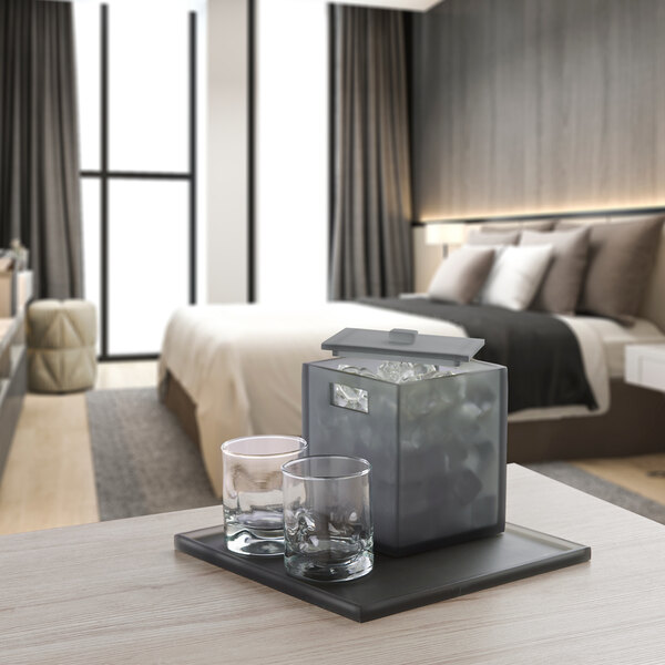 A table with a Focus Hospitality Smoke Collection matte gray square beverage tray holding an ice bucket and glasses.