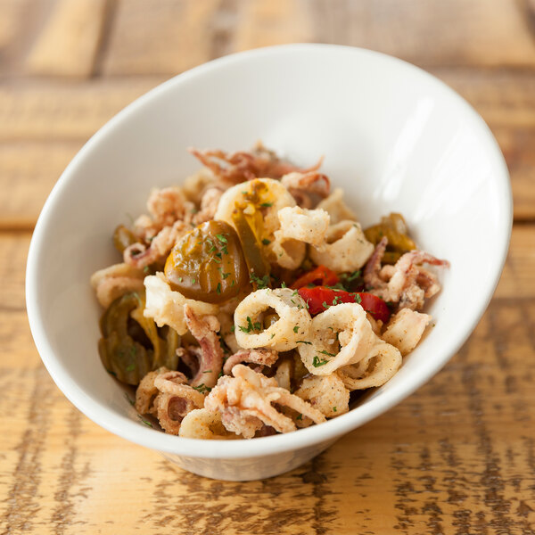 A white porcelain 10 Strawberry Street Whittier pinch bowl filled with food on a table.