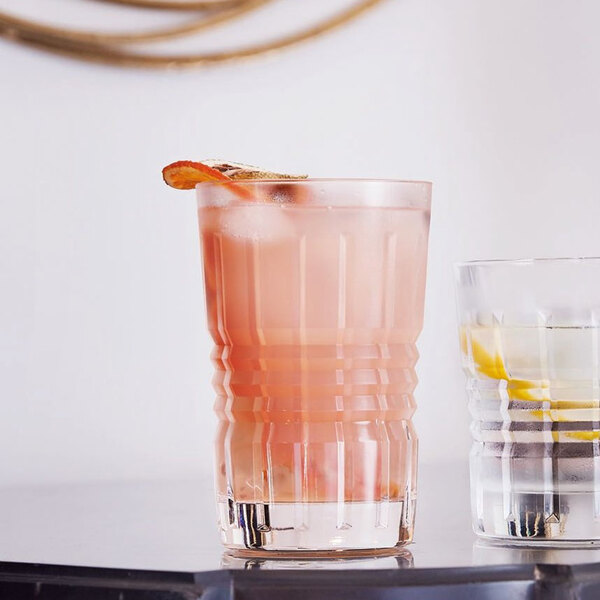 Two Chef & Sommelier Cristal d'Arques highball glasses filled with pink drinks on a bar counter.