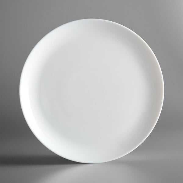 A close up of a white Arcoroc round rimless glass plate.