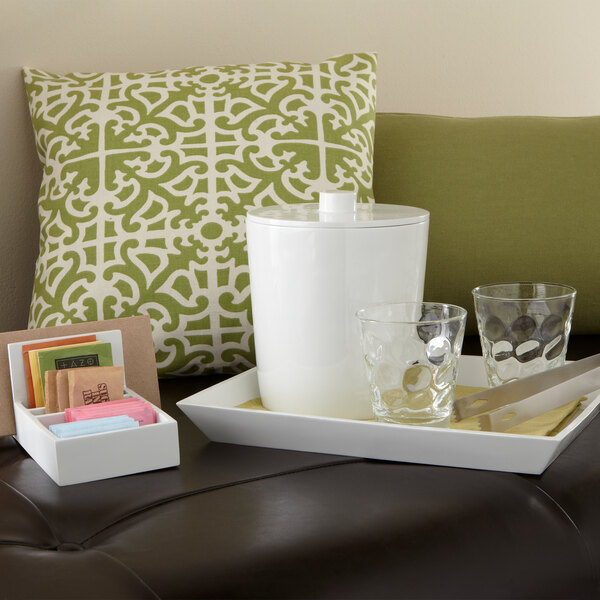 A white melamine condiment caddy with tea and glasses on a couch.