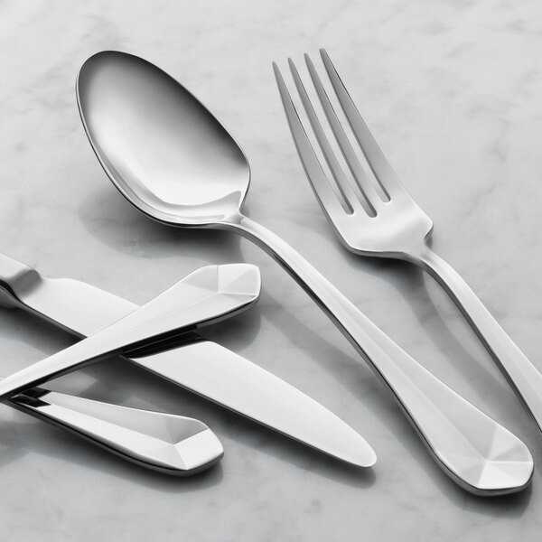 A case of 12 Reserve by Libbey stainless steel dinner spoons on a marble surface.