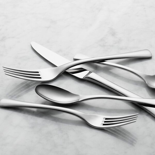 A set of Reserve by Libbey stainless steel dinner forks on a white surface.