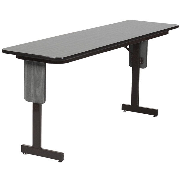 A rectangular Correll seminar table with New England Driftwood finish and black panel legs.