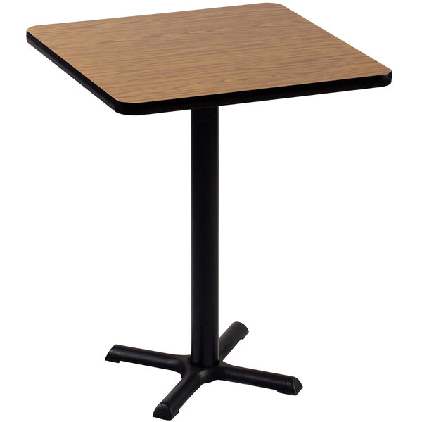 A Correll bar height table with a medium oak finish top and black base.