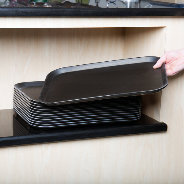 A person holding a Cambro black non-skid serving tray.