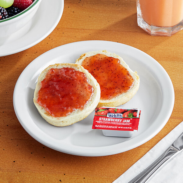A plate with a piece of bread spread with Strawberry Jam.