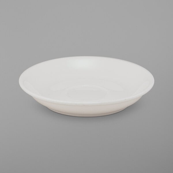 A bright white porcelain saucer with a small rim on a white surface.