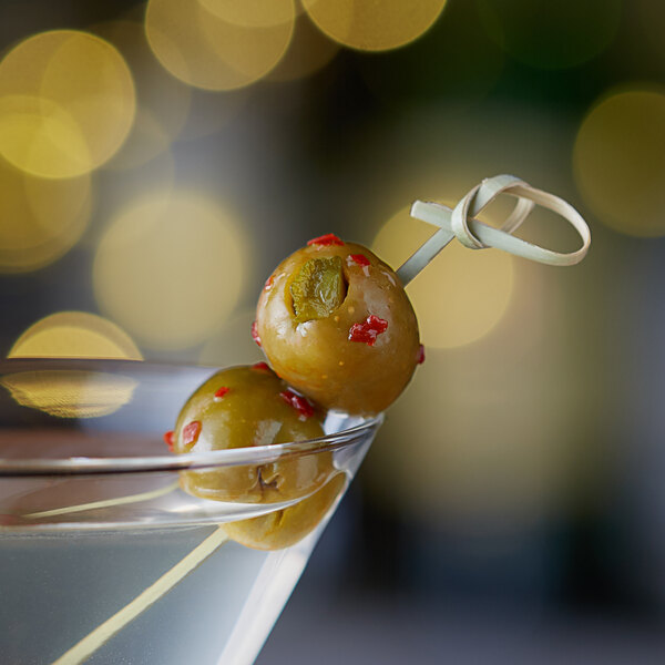 A martini with Belosa Sweet & Spicy Pickle Stuffed Queen Olives on a stick.