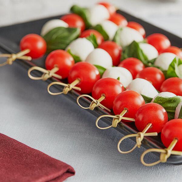 A plate of tomatoes and cheese skewers with tomatoes on Royal Paper Eco-Friendly Bamboo Food Picks.