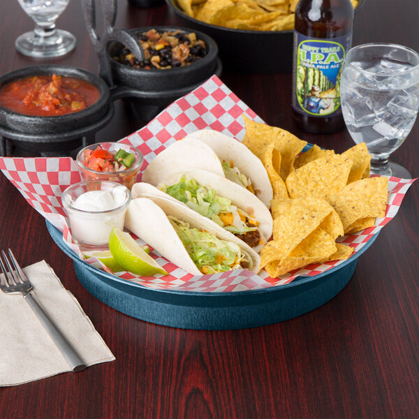 A table with a plate of tacos and a blueberry round deli server filled with red sauce on it.