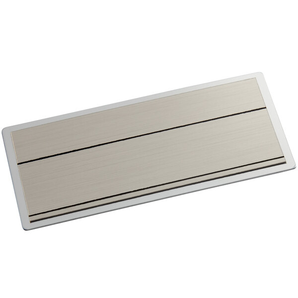 A rectangular silver metal nametag with black lines.