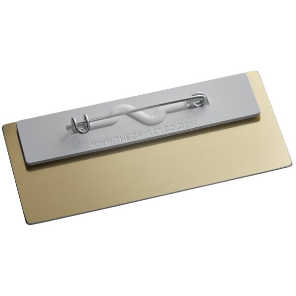 A gold metal rectangle nametag with a white paper insert and wire clip.