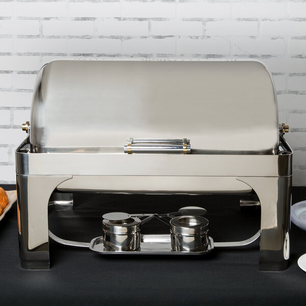 A Vollrath silver New York roll top chafer on a table with food inside.