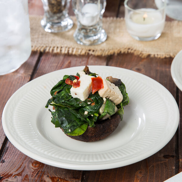 An ivory embossed rim china bread and butter plate with a mushroom, spinach, and cheese dish.