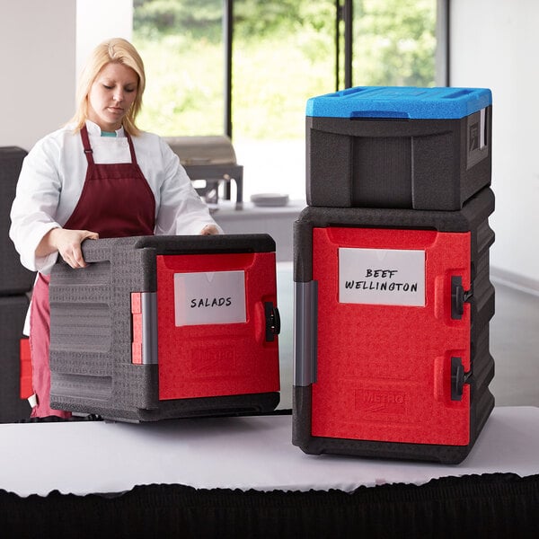 A woman holding a red and black Metro Mightylite Pan Carrier with a blue top.