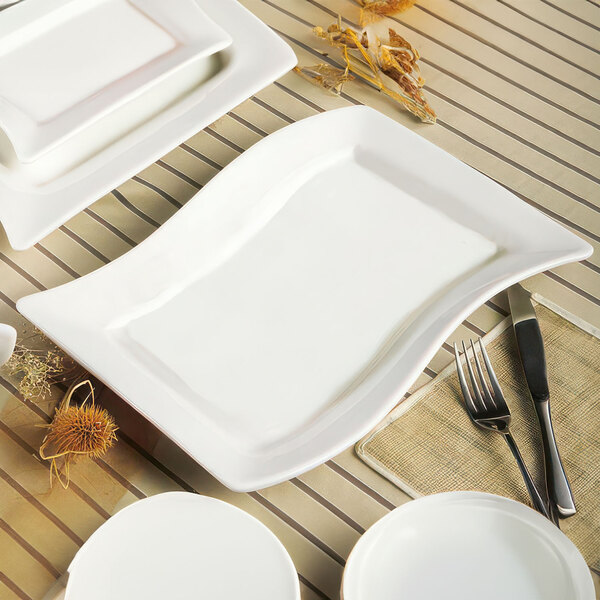 A rectangular ivory stoneware platter with a fork and knife on it on a table.