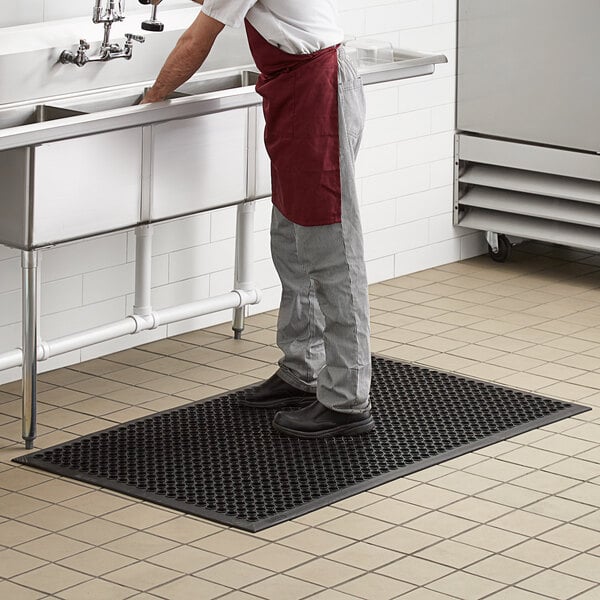 restaurant worker washing dishes standing on non-slip floor mat