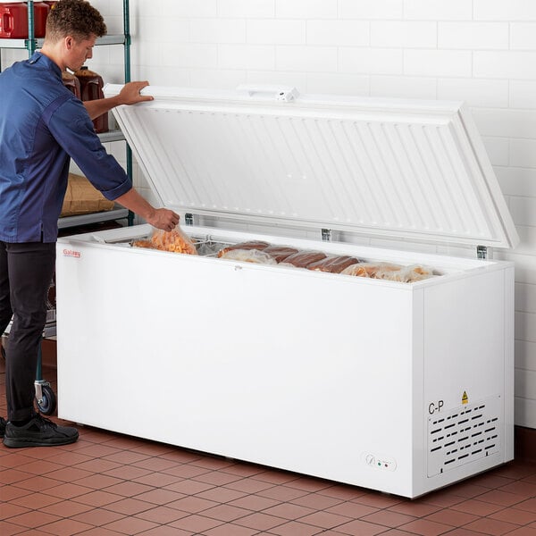 A man opening a Galaxy commercial chest freezer in a deli room.