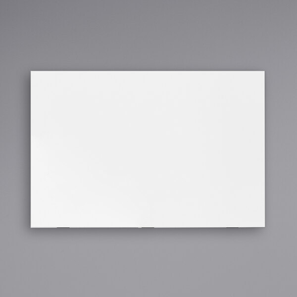 A white rectangular Luxor magnetic glass presentation board with black border on a gray wall.