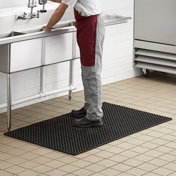 Dish washer standing on a rubber wet area anti-fatigue mat