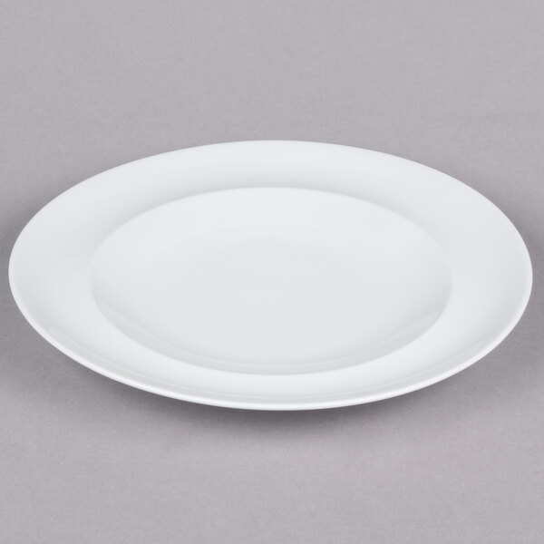 An Arcoroc white porcelain side plate with a rim on a gray surface.