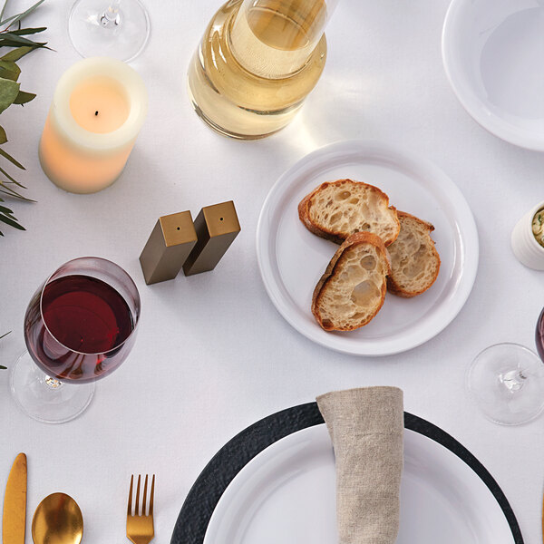 A white table set with American Metalcraft white melamine bread and butter plates, bread, and a knife.