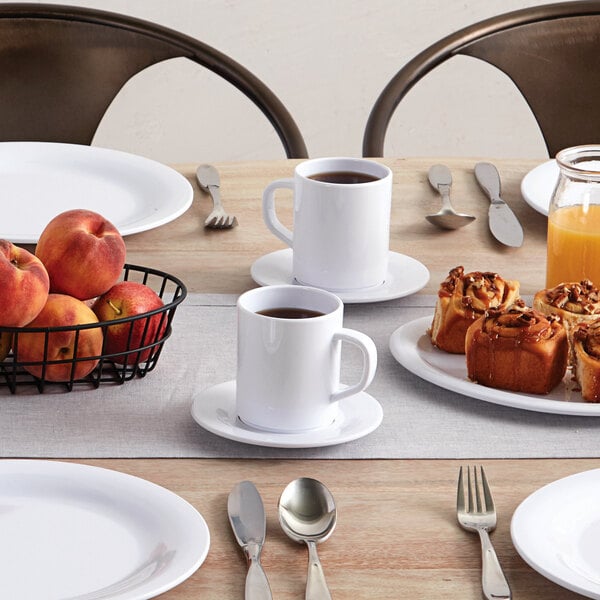 A white American Metalcraft Tritan mug with a handle on a table with plates and bowls.