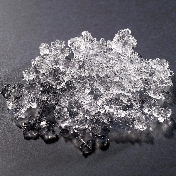 A pile of flake ice from a Hoshizaki remote condenser ice machine on a black surface.