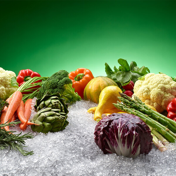 A group of vegetables on ice with a Hoshizaki remote condenser ice machine in the background.