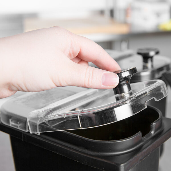 A hand holding a lid to a black container.