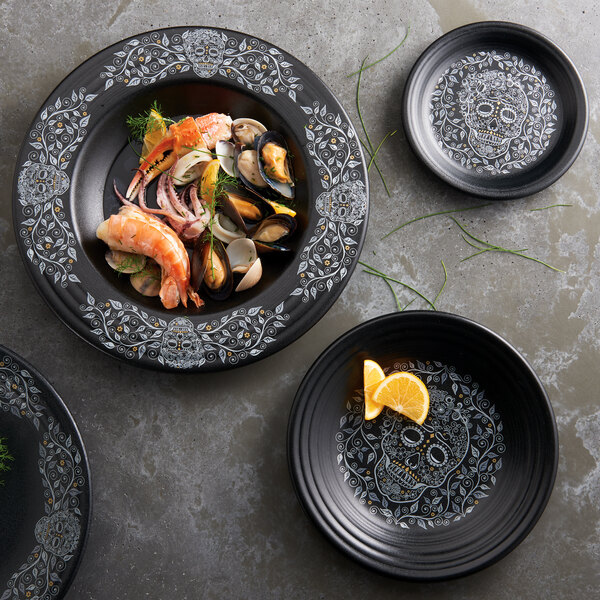 A Fiesta china ramekin with a skull and vine design on it filled with seafood.