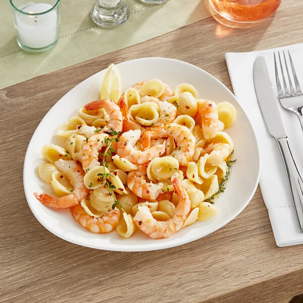 A plate of Acopa Nova stoneware with shrimp and pasta with lemon slices.