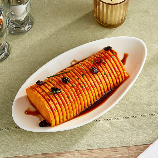 An Acopa Nova cream white triangle stoneware plate with a sweet potato dish on it.