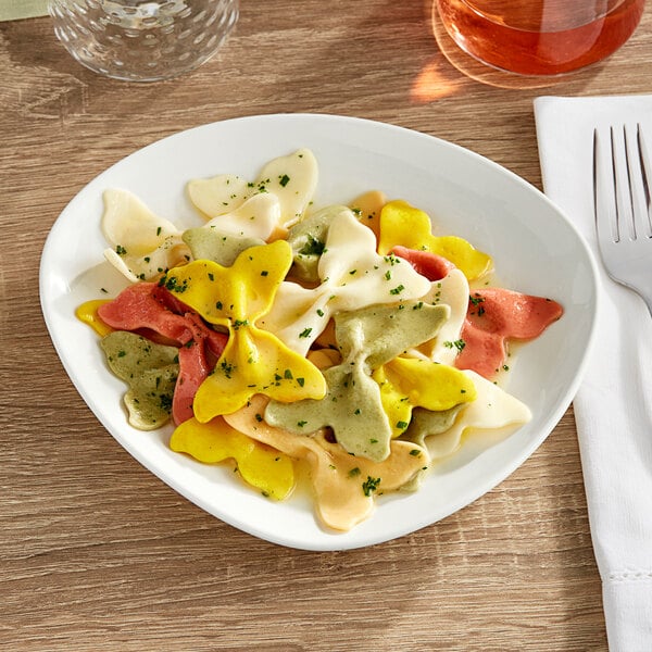 An Acopa Nova cream white stoneware plate with pasta, a fork, and a glass of wine.