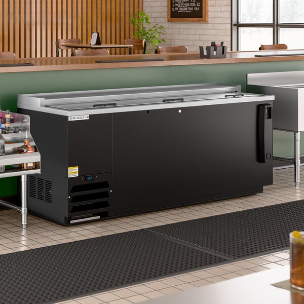 A large black deep well bottle cooler with sliding lids, designed for commercial beverage storage.