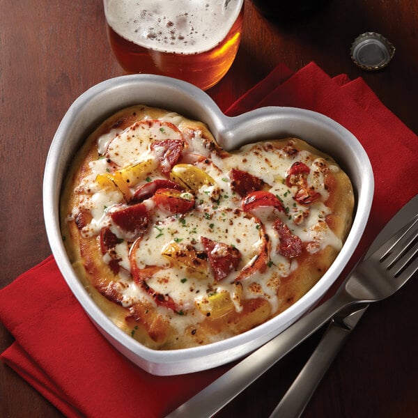 A heart shaped pizza in an American Metalcraft aluminum cake pan.