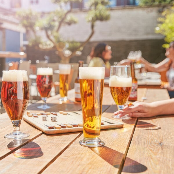 Arcoroc Linz footed pilsner glasses filled with beer on a table in a brewery tasting room.