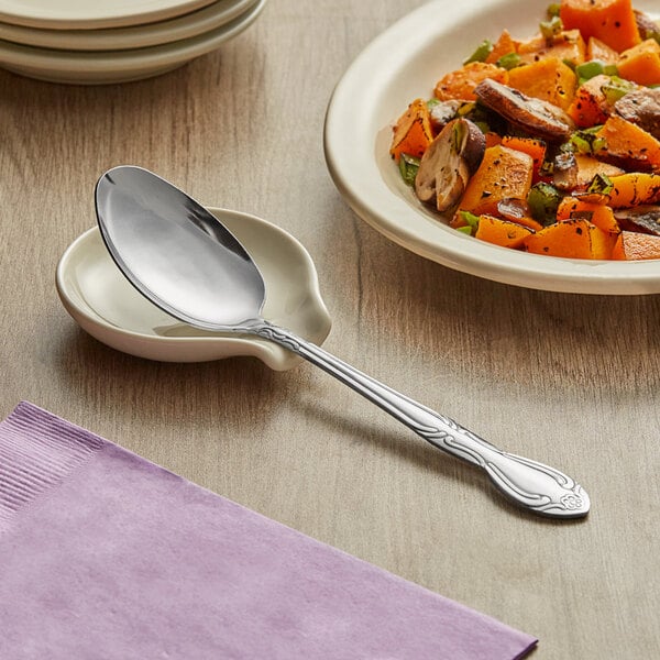 A Choice Bethany stainless steel serving spoon in a bowl of food on a table.