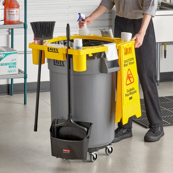 A Lavex 44 gallon gray round commercial trash can with a yellow rim caddy attached.