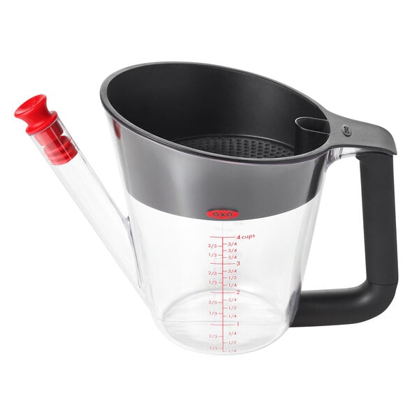 An OXO clear plastic fat separator with a red handle.