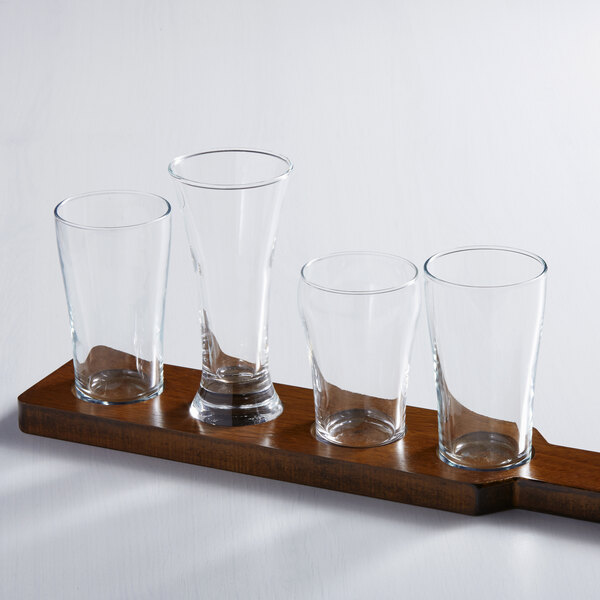 A wooden board with Arcoroc Bell beer tasting glasses on it.