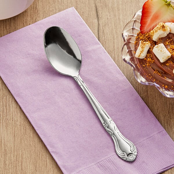 A Choice Bethany stainless steel teaspoon on a napkin next to a bowl of chocolate dessert.